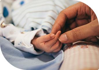 Baby's hand holding adult's finger